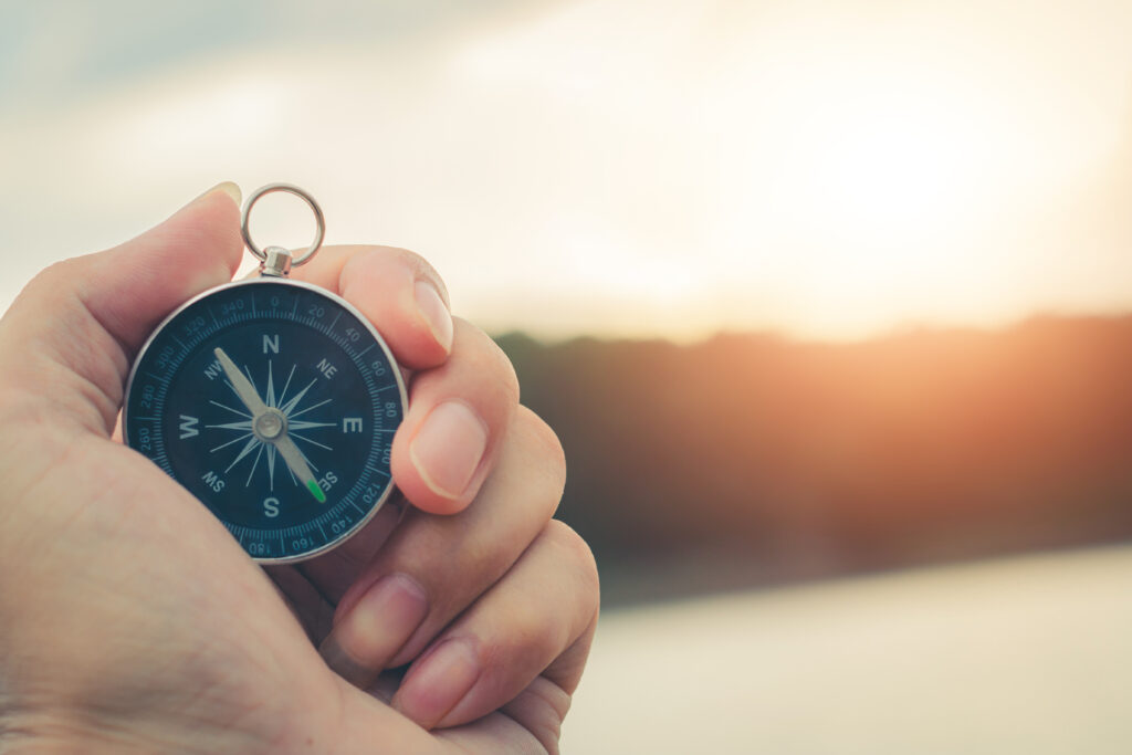 Compass of tourists on mountain at sunset sky.